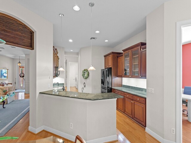 kitchen with kitchen peninsula, light hardwood / wood-style flooring, and decorative light fixtures