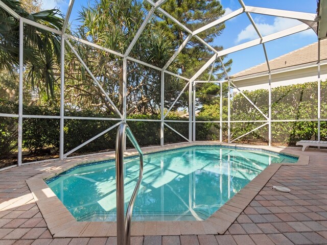 view of pool with glass enclosure and a patio area