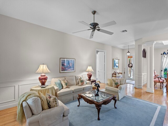 living room featuring decorative columns, ceiling fan, and light hardwood / wood-style flooring