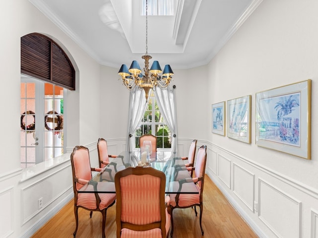 dining space with light wood-type flooring, an inviting chandelier, and crown molding