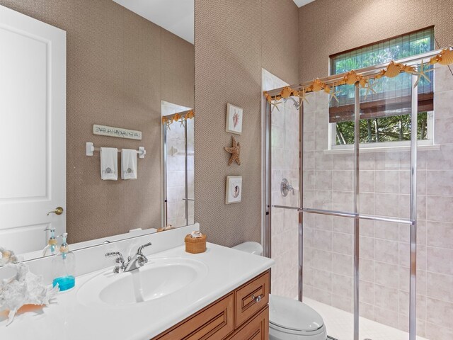 bathroom with vanity, toilet, and a shower with shower door