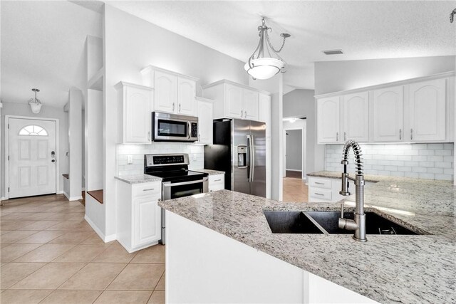 115 Larchmont Ter, Sebastian, FL 32958 - kitchen featuring stainless steel appliances, vaulted ceiling, light stone counters, tasteful backsplash, and light tile patterned flooring