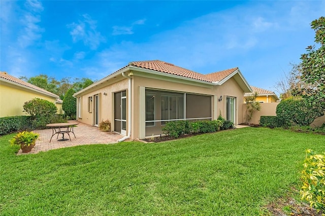 back of property featuring a yard, a sunroom, and a patio