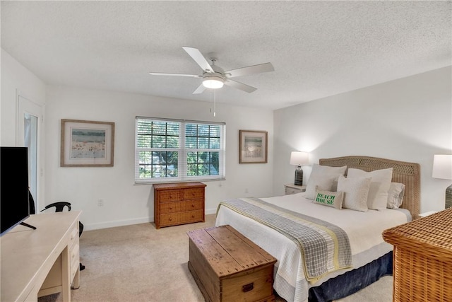 bedroom with ceiling fan, light colored carpet, and a textured ceiling