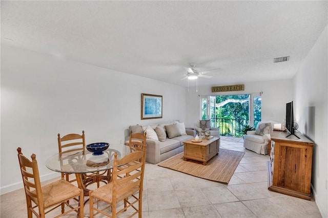 living room featuring ceiling fan, light tile patterned floors, and a textured ceiling