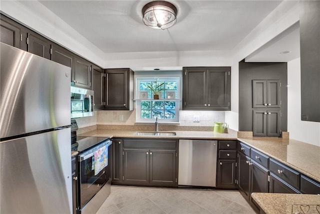 kitchen with appliances with stainless steel finishes, backsplash, dark brown cabinetry, sink, and light tile patterned flooring