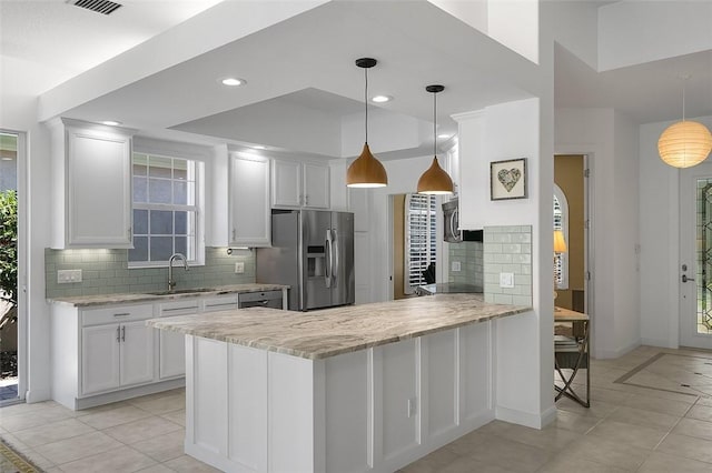 kitchen featuring stainless steel fridge with ice dispenser, a sink, white cabinetry, decorative backsplash, and light stone counters