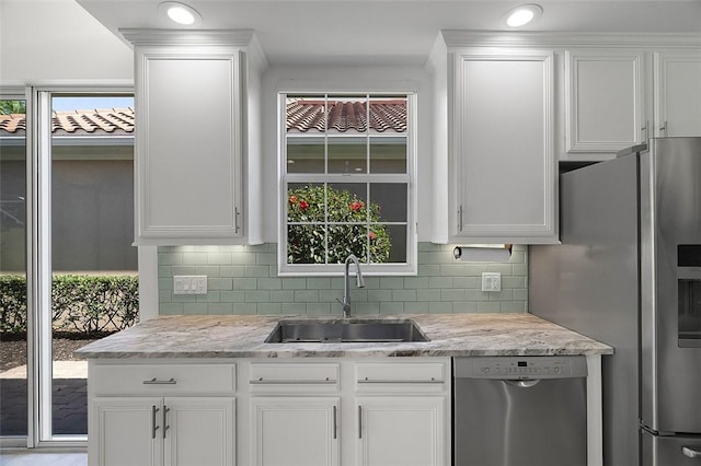 kitchen with stainless steel appliances, white cabinets, a sink, and decorative backsplash