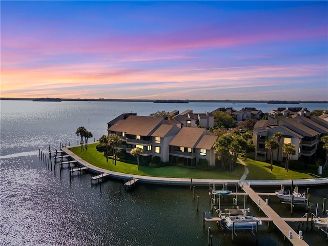 aerial view at dusk with a water view and a residential view