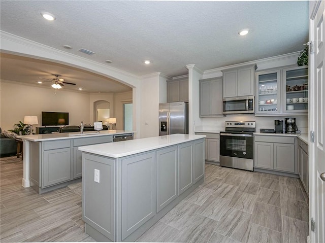 kitchen with gray cabinets, ceiling fan, a center island, and stainless steel appliances