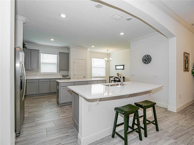 kitchen featuring a wealth of natural light, a center island with sink, hanging light fixtures, and sink