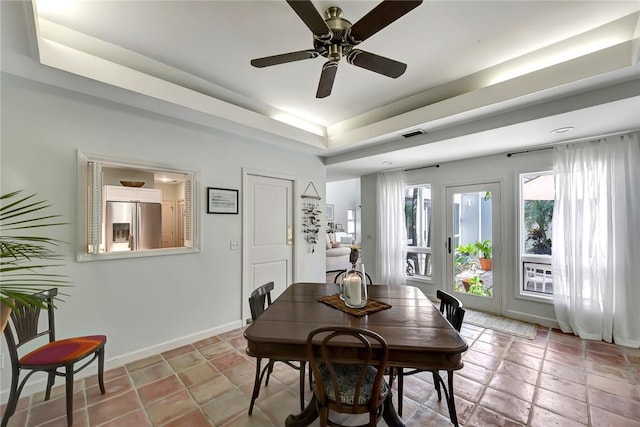 dining room featuring a tray ceiling, ceiling fan, and light tile patterned flooring