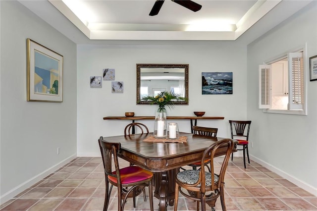 dining space with a raised ceiling, light tile patterned flooring, and ceiling fan