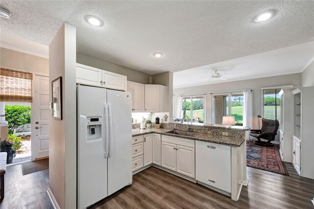 kitchen with kitchen peninsula, sink, dark hardwood / wood-style floors, white cabinetry, and white appliances