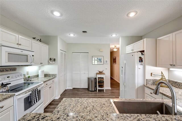 kitchen with light stone counters, a textured ceiling, sink, white cabinetry, and white appliances