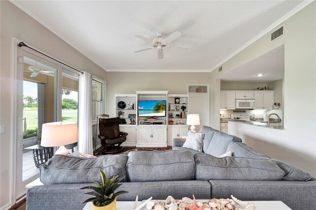 living room featuring sink, ornamental molding, ceiling fan, a textured ceiling, and hardwood / wood-style floors