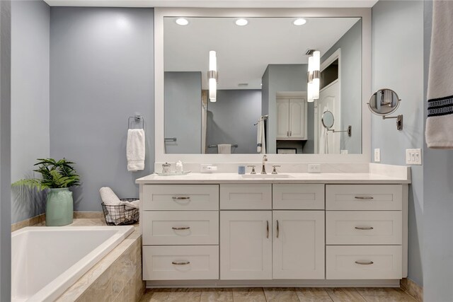 bathroom featuring vanity and tiled bath