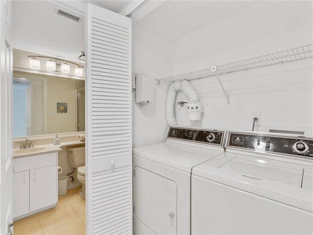 clothes washing area featuring light tile patterned floors, washer and clothes dryer, and sink