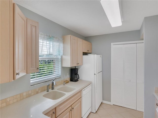 kitchen with light brown cabinetry, sink, and white dishwasher