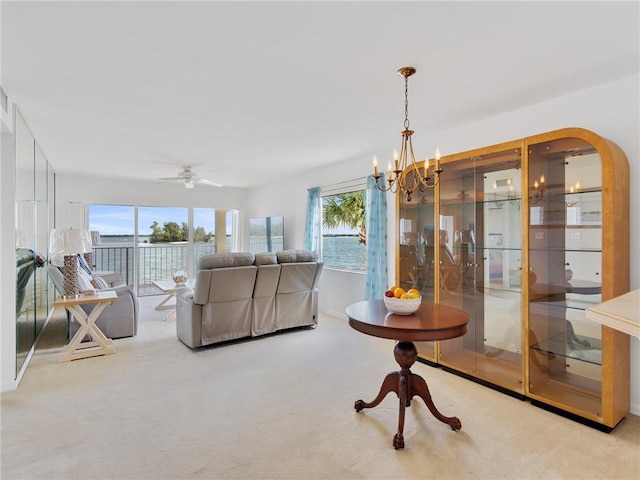 living room featuring ceiling fan with notable chandelier, light carpet, and a wealth of natural light