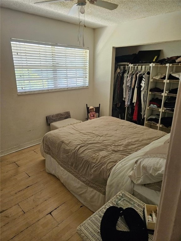 bedroom with ceiling fan, a closet, wood-type flooring, and multiple windows