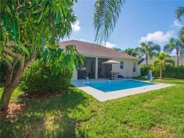 back of property with a yard, a patio, a fenced in pool, and a sunroom