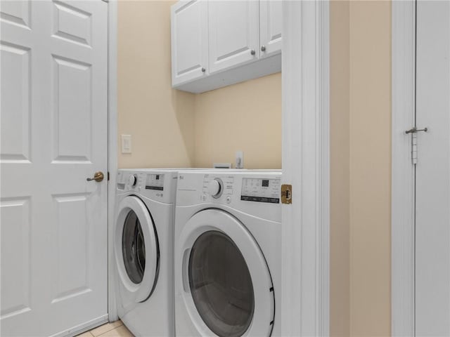 laundry room featuring washing machine and clothes dryer, light tile patterned floors, and cabinets