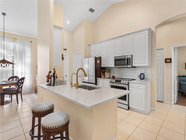 kitchen with white cabinetry, sink, stainless steel appliances, kitchen peninsula, and decorative light fixtures