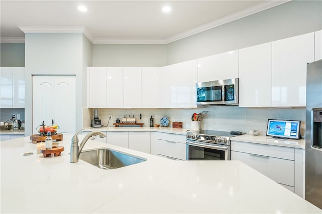 kitchen featuring stainless steel appliances, sink, tasteful backsplash, crown molding, and white cabinetry