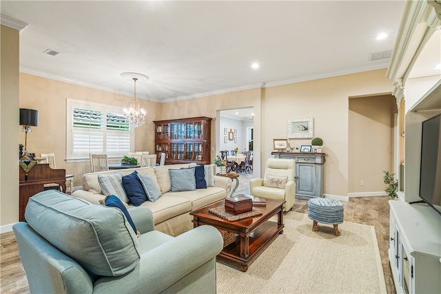 living room with light wood-type flooring, a notable chandelier, and ornamental molding