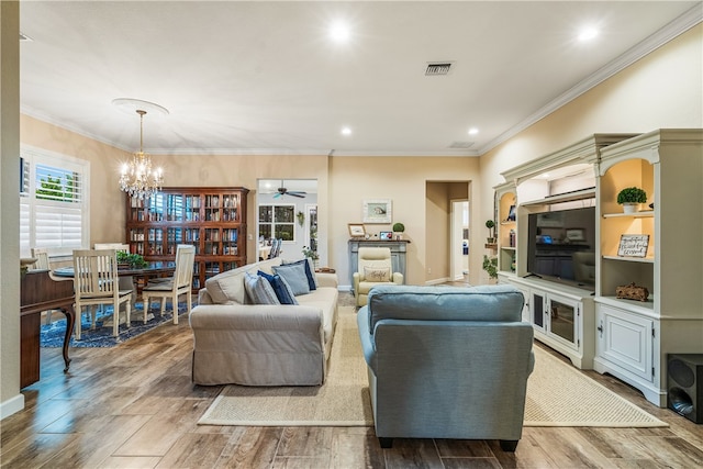 living room with hardwood / wood-style floors, ceiling fan with notable chandelier, and crown molding