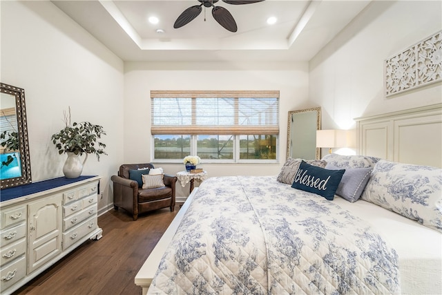 bedroom with ceiling fan, dark hardwood / wood-style floors, and a tray ceiling