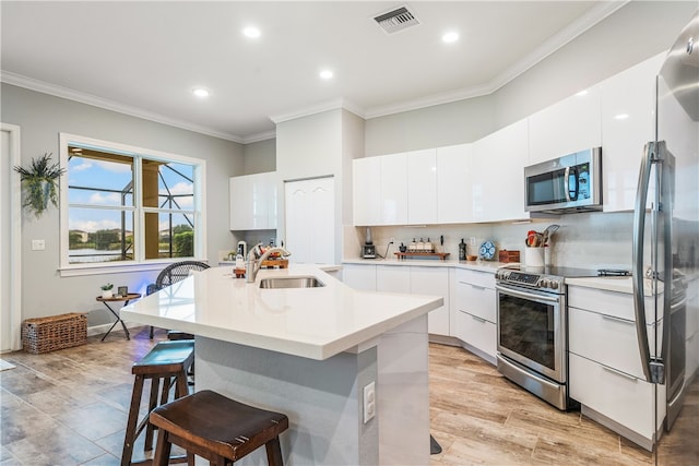 kitchen with white cabinets, sink, appliances with stainless steel finishes, and an island with sink