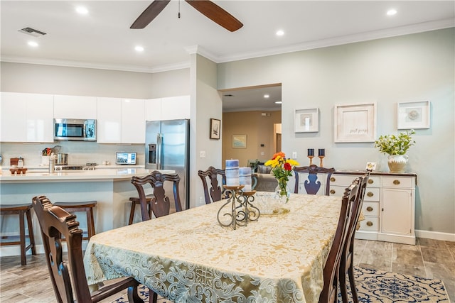 dining space with light wood-type flooring, ceiling fan, and crown molding