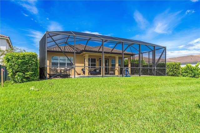 back of property with a patio area, a lawn, and a lanai