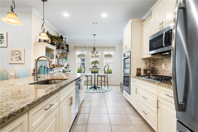 kitchen featuring ornamental molding, appliances with stainless steel finishes, light stone countertops, hanging light fixtures, and sink