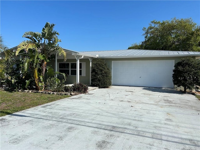 view of front facade featuring stucco siding, metal roof, concrete driveway, and an attached garage