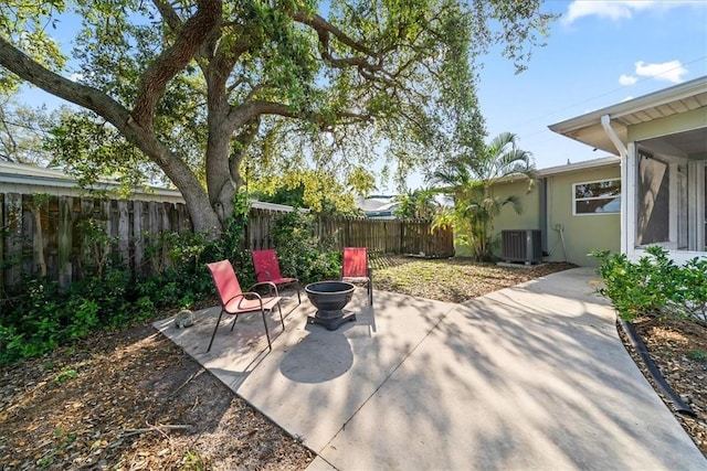 view of patio with fence private yard, a fire pit, and central AC