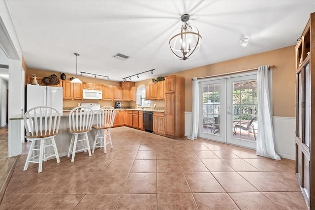 kitchen with white appliances, visible vents, wainscoting, french doors, and light tile patterned flooring