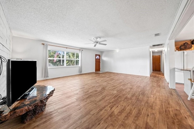 unfurnished living room with light wood-style floors, visible vents, ceiling fan, and a textured ceiling