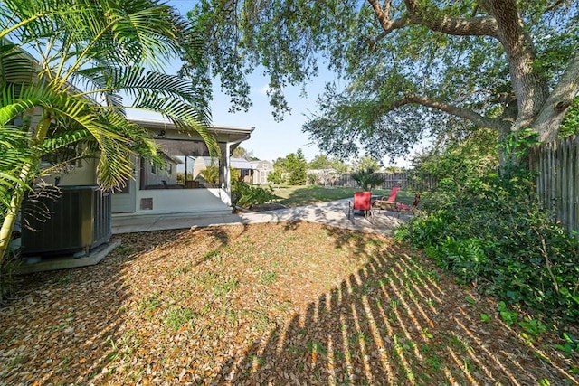 view of yard with central AC unit, a patio area, a fenced backyard, and a sunroom