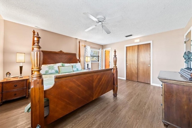 bedroom featuring a textured ceiling, ceiling fan, wood finished floors, visible vents, and a closet