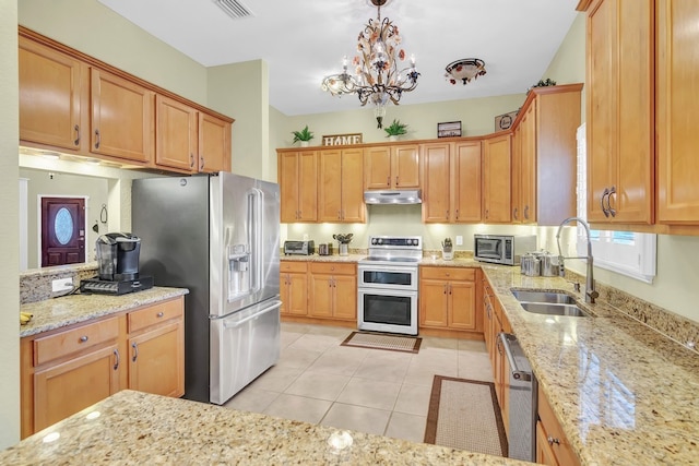 kitchen featuring stainless steel appliances, a notable chandelier, sink, light stone countertops, and decorative light fixtures