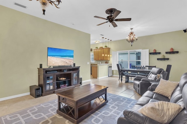 tiled living room with ceiling fan with notable chandelier