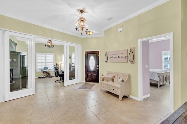 foyer entrance with an inviting chandelier, light tile patterned floors, a healthy amount of sunlight, and crown molding