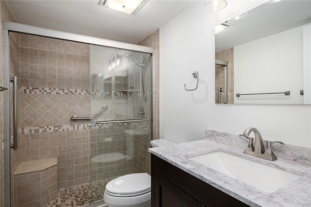 bathroom featuring vanity, a shower with door, and toilet