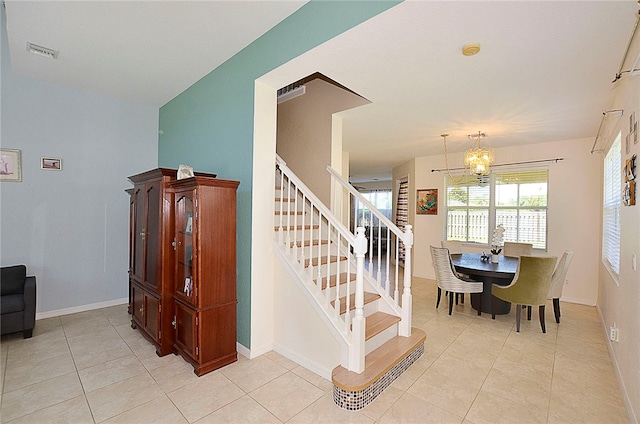 stairs featuring tile patterned floors and an inviting chandelier