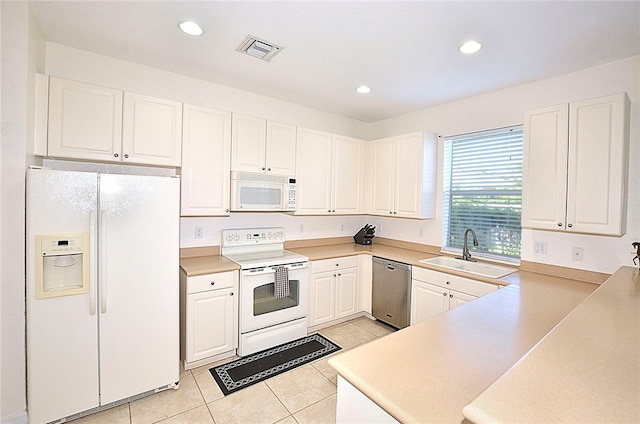 kitchen featuring white cabinetry, sink, kitchen peninsula, light tile patterned floors, and white appliances