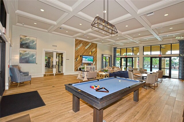 recreation room with a towering ceiling, french doors, beamed ceiling, and light wood-type flooring