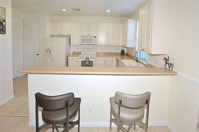 kitchen with white cabinets, white appliances, sink, and kitchen peninsula